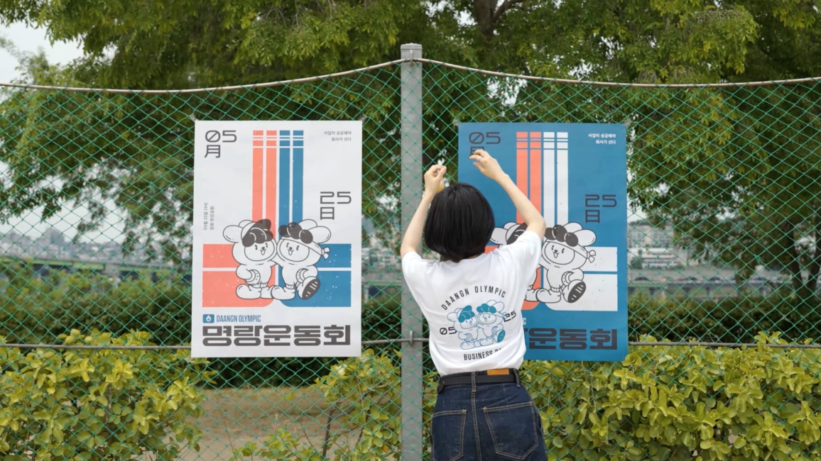 당근마켓 명랑운동회 포스터를 벽에 붙이고 있어요